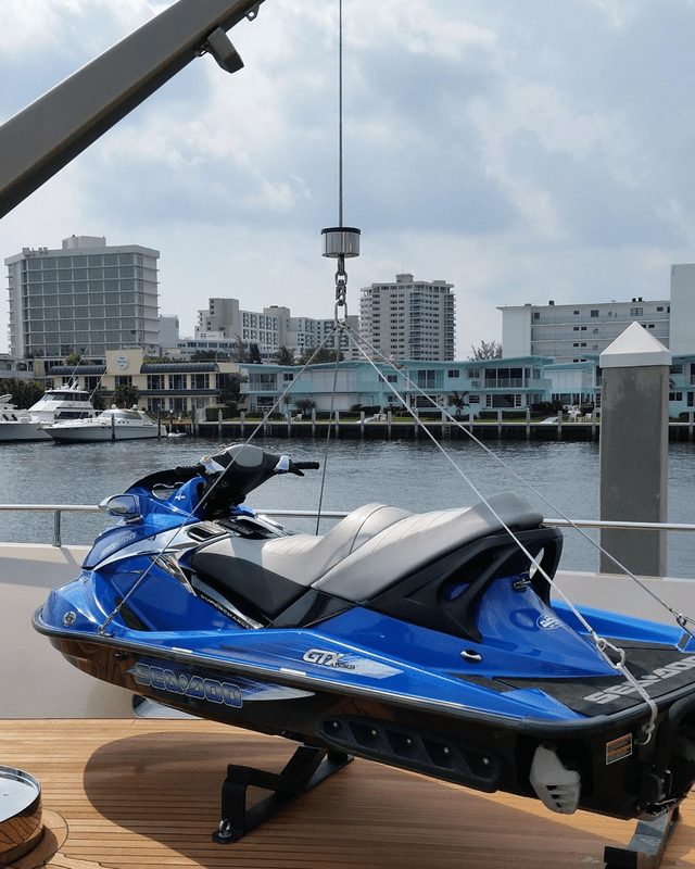 Blue jet ski parked near waterfront with city skyline.