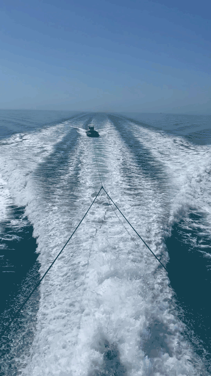 View of a boat's wake from the stern on a calm sea.