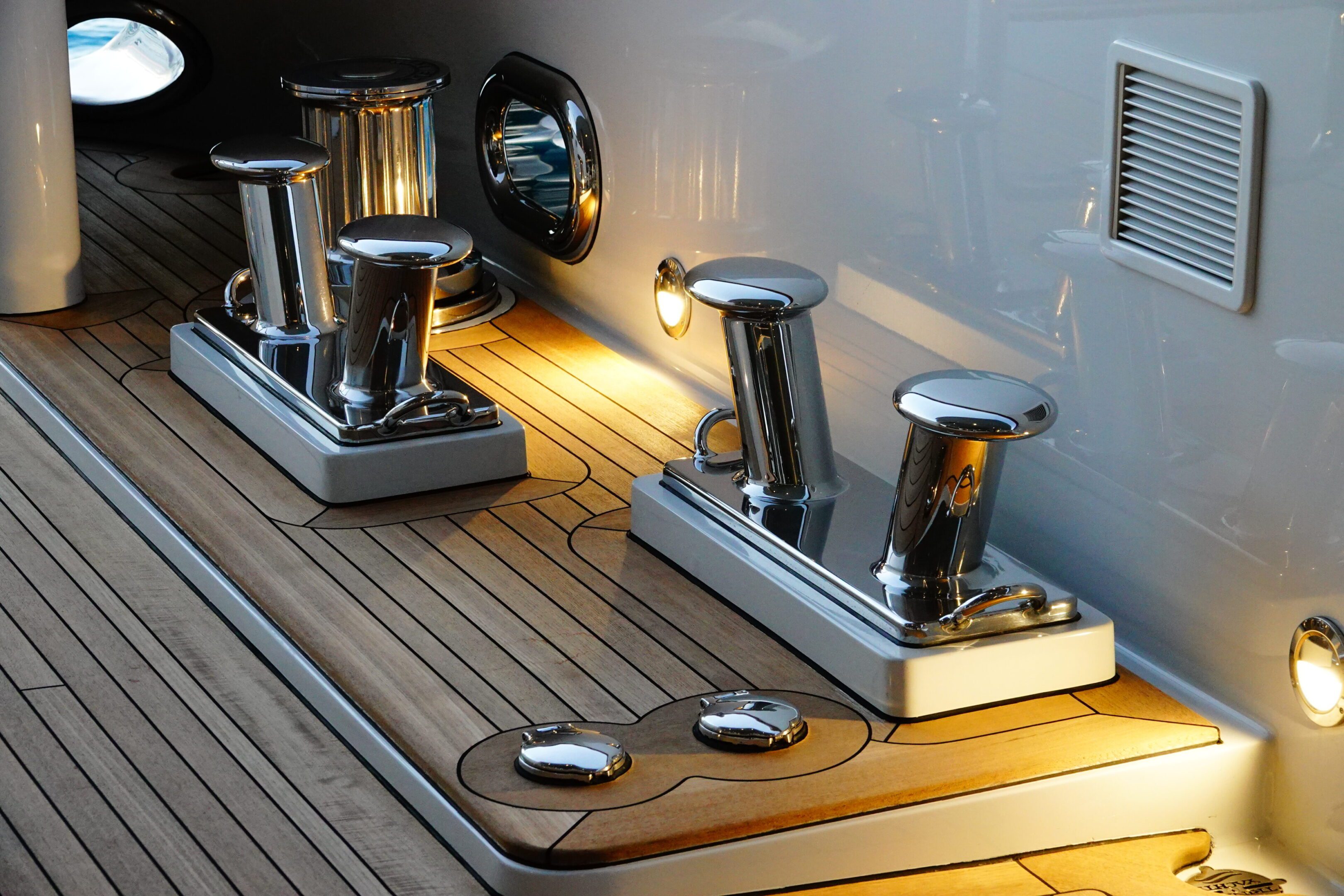Shiny chrome boat fittings on a wooden deck under soft lighting.