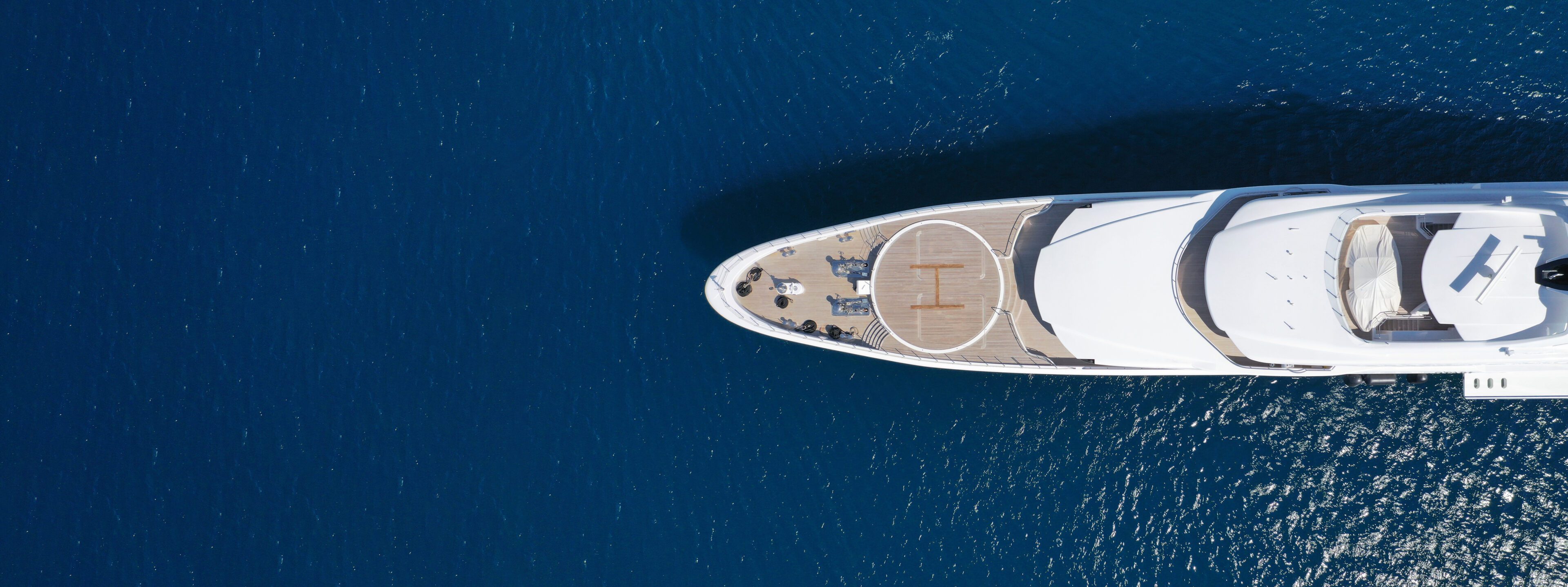 Aerial view of a luxury yacht on deep blue water.