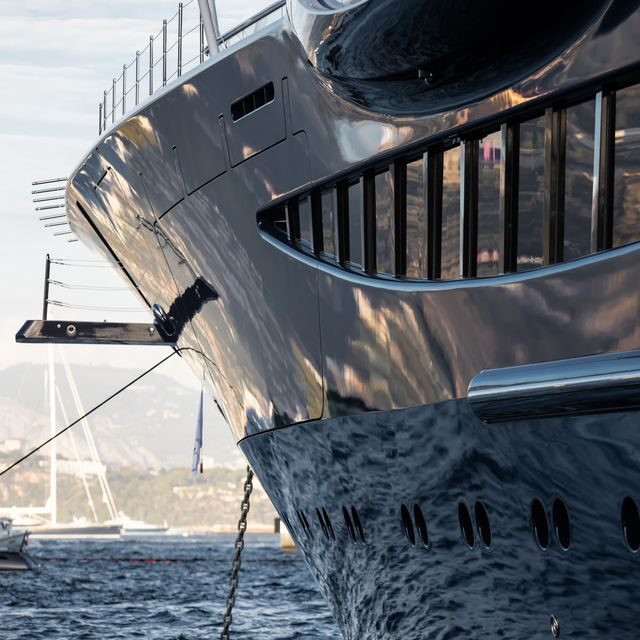 Close-up of a sleek yacht's bow reflecting sunlight on the water.